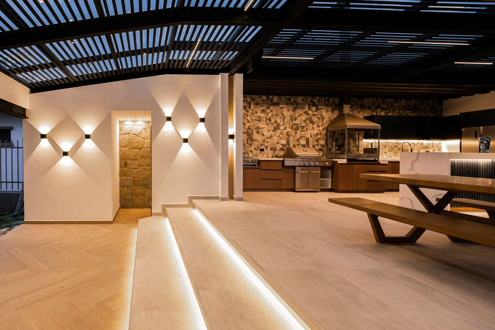 Covered outdoor living area with a kitchen, dining table and seating