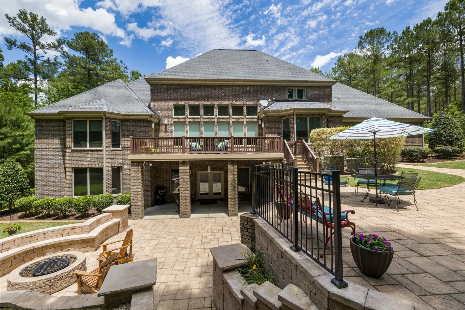 Paver terrace with a fire pit and seating beside a landscaped yard