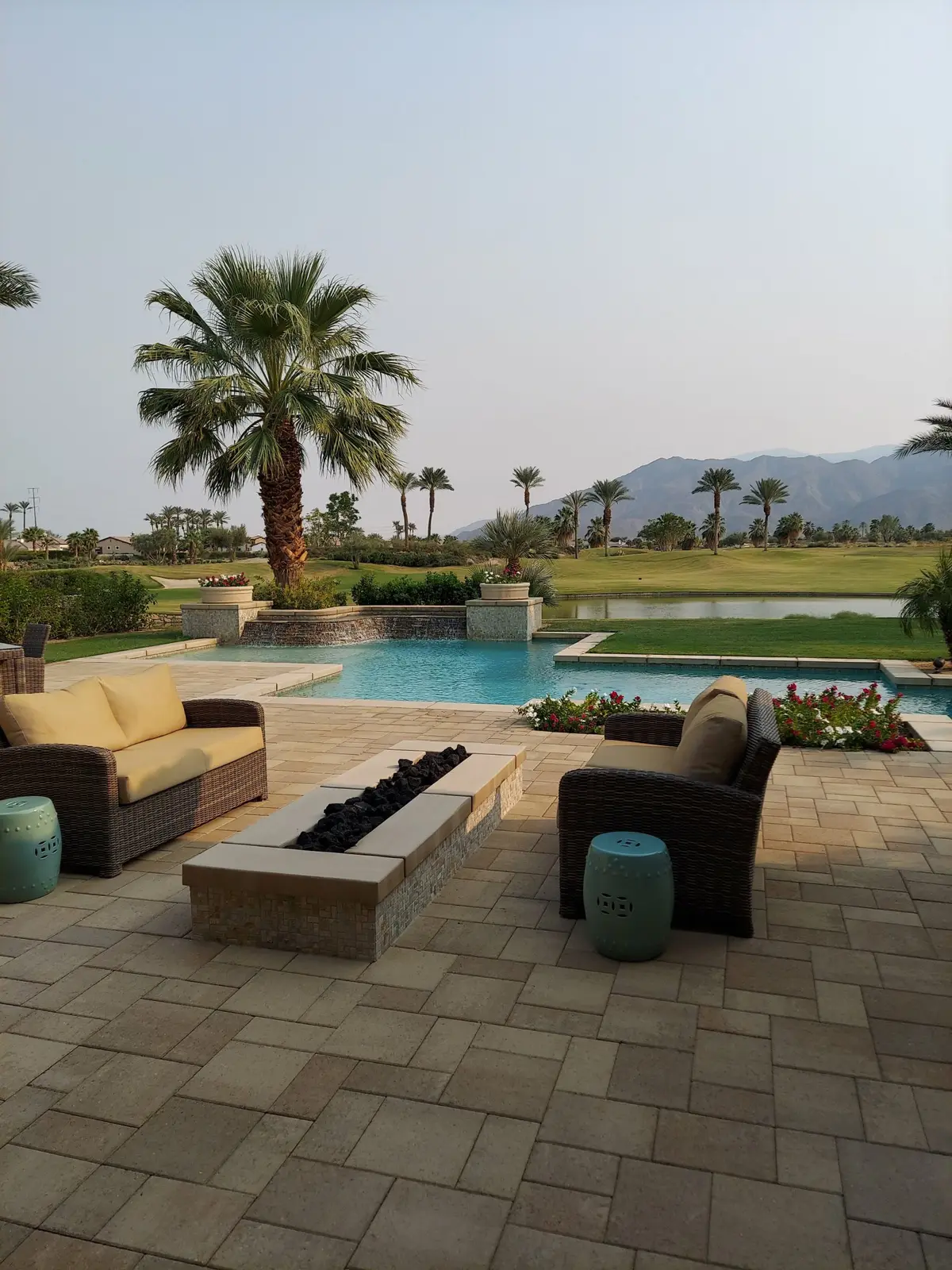 Desert backyard with a pool, palm trees, pavers and a fire pit
